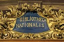 BIBLIOTHECA NATIONALIS, zlacená kartuš s latinským nápisem, označující Národní knihovnu založenou K. R. Ungarem, Barokní knihovní sál